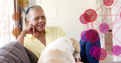 Senior woman relaxing with dog on couch at home, natural light, magenta network overlay