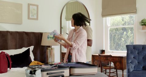 Couple packing suitcase for trip in cozy bedroom