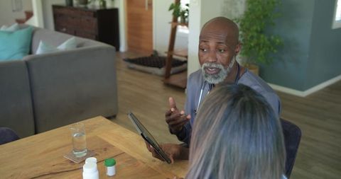 Clinician reviewing medications with senior patient using tablet during home visit