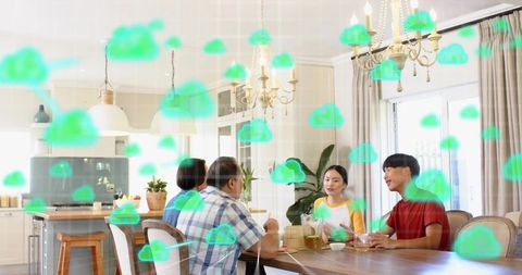 Family of four dining and talking with green cloud overlays conveying cloud computing