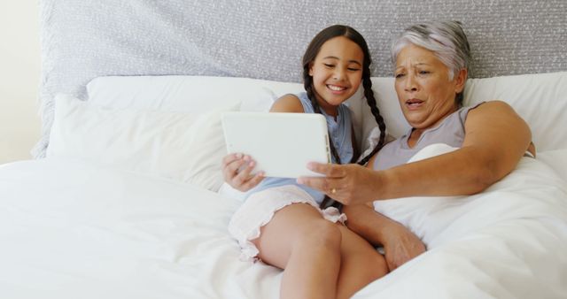 Grandmother and Granddaughter Relaxing on Bed with Tablet - Download Free Stock Images Pikwizard.com