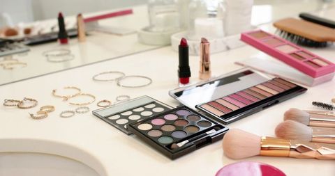 Makeup vanity flatlay showcasing colorful eyeshadow palettes, rose-gold brushes and jewelry