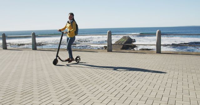 Young woman riding an electric scooter along a seaside pathway on a sunny day. This image is ideal for illustrating topics related to eco-friendly transportation, outdoor leisure activities, travel, adventure, coastal lifestyle, youthful enjoyment, and urban mobility.