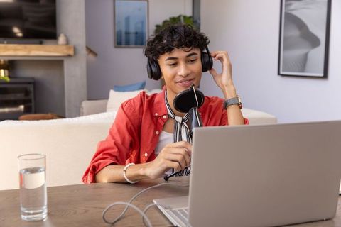 Man hosting podcast at home with laptop and microphone
