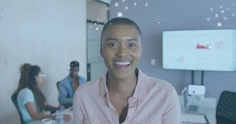 Smiling professional with digital icons in modern office workspace