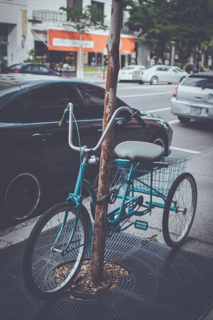 This scene shows an eye-catching retro tricycle parked under a tree in an urban street. Ideal for designers and creatives needing urban scenes or transportation themes. Perfect for blogs, advertising, and websites focusing on city life, vintage transport, eco-friendly commuting, and urban cycling.