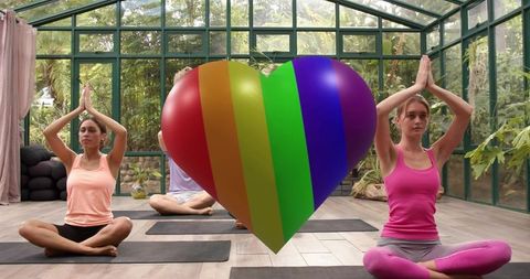Practicing Yoga in Glasshouse with Rainbow Heart Symbolizing Pride and Mindful Wellness
