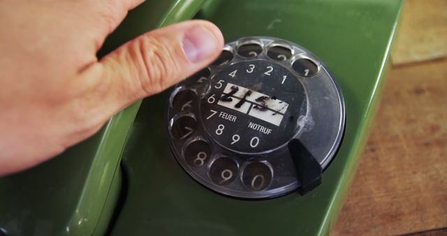 A person is dialing a number on a vintage rotary phone, with copy space. Rotary phones are a nostalgic reminder of communication before the digital age.