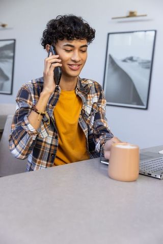 Young man using smartphone at modern home workspace for inspiration