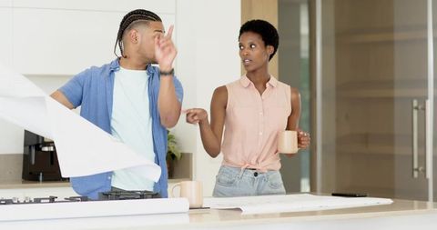 Couple Discussing Blueprints in Modern Kitchen