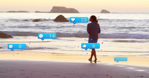 Woman Strolling Beach with Social Media Notifications at Sunset