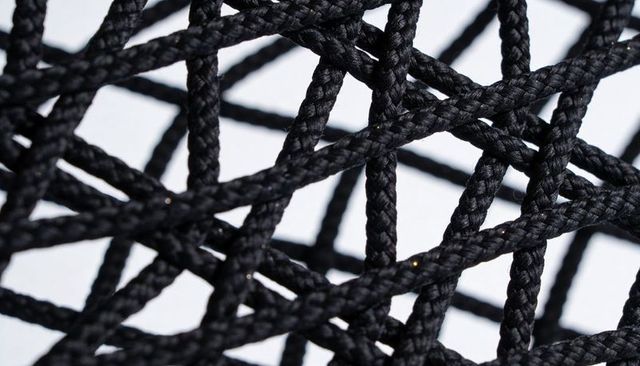 Macro black braided cord lattice with geometric woven texture, high-contrast close-up