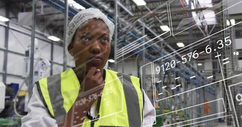 Woman engineer inspecting digital analytics in factory wearing hairnet and hi-vis vest