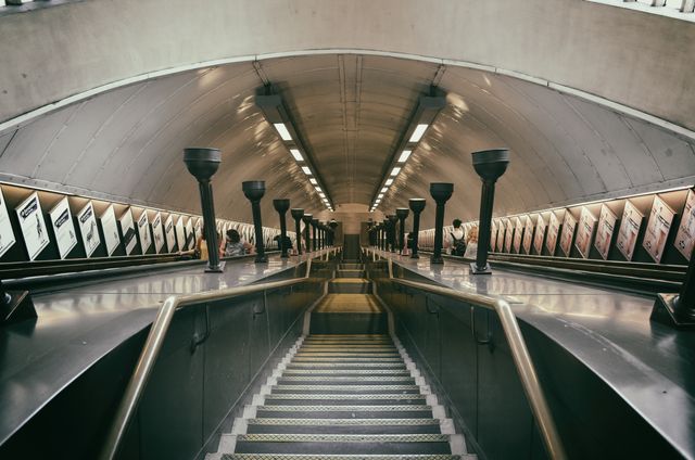 Pictured in this photo is a modern metro escalator leading down into an underground station, showcasing clean architectural lines and symmetry. This urban setting highlights aspects of public transport infrastructure, making it suitable for use in projects about city life, transport systems, commuting, or urban architecture. It can also be featured in presentations and content focused on public transportation systems' efficiency and design.