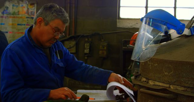 Male worker writing on clipboard in foundry workshop. Coworker standing in background 4k
