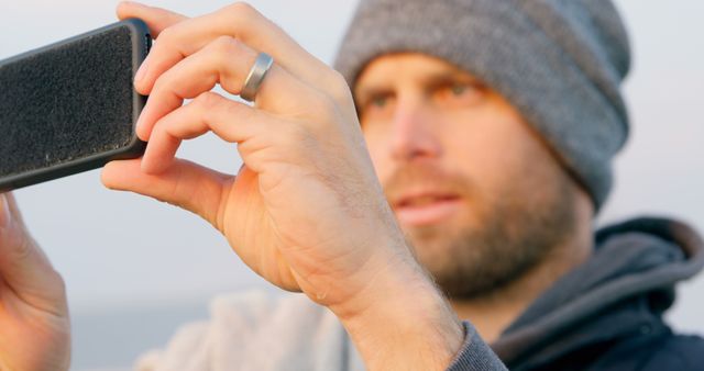 Man Taking Picture with Smartphone, Beanie and Focused Expression - Download Free Stock Images Pikwizard.com