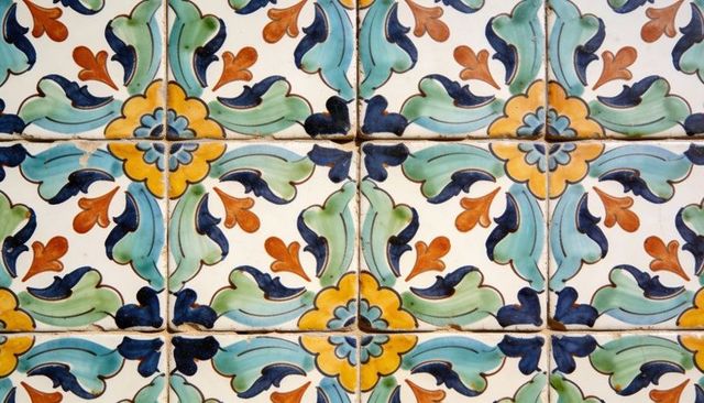 Handpainted mediterranean ceramic tile with floral motif, symmetric mosaic and worn grout