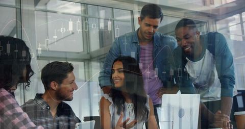 Diverse team analyzing market charts collaborating around laptop in bright office