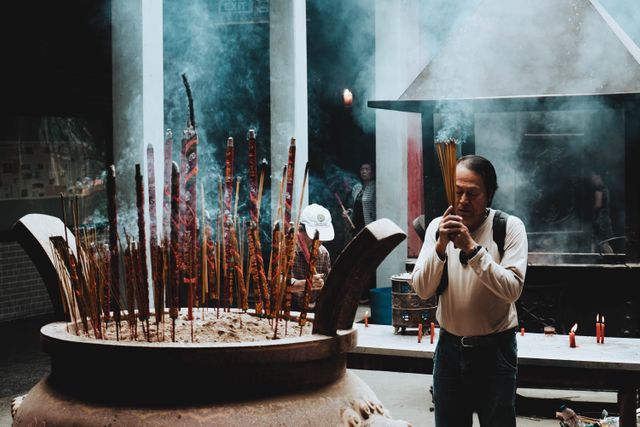 Man Praying with Incense Sticks in Traditional Asian Temple - Download Free Stock Images Pikwizard.com