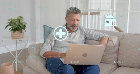Middle-aged man using laptop on sofa displaying telehealth interface and wellness data