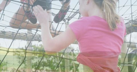 Woman navigating rope net in outdoor obstacle course