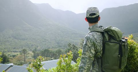 Exploring soldier overlooking mountain landscape in camouflage