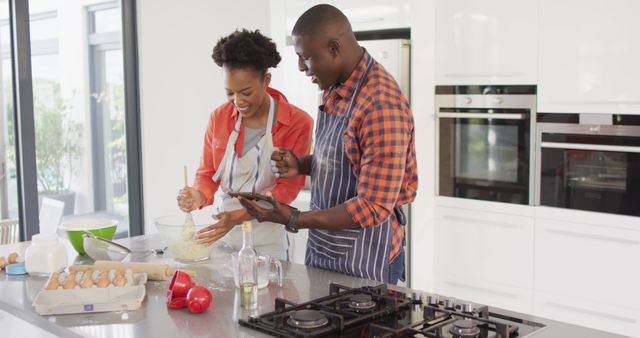Image of happy african american couple baking together with tablet. Love, relationship and spending quality time together concept.