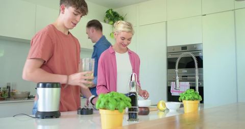 Family preparing smoothie and cooking together at bright modern kitchen island