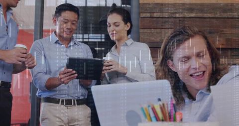 Diverse team collaborating with tablet and laptop sharing ideas with finance data overlay
