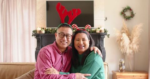 Diverse Couple in Festive Headbands Embracing Cozy Holiday Season at Home