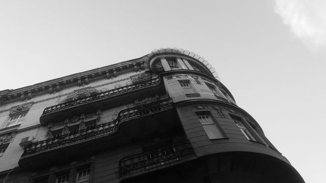 This black-and-white image showcases a historic European building with classic architectural design and iron balconies. The scene captures the elegance and charm of urban heritage, making it ideal for use in projects related to travel, architecture, history, and culture. It can be used in brochures, websites, blogs, or prints that emphasize the beauty of historic cityscapes and architectural design.