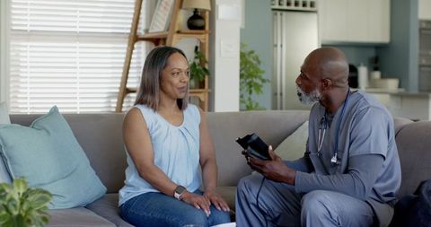 African american clinician demonstrating blood pressure monitor during home visit