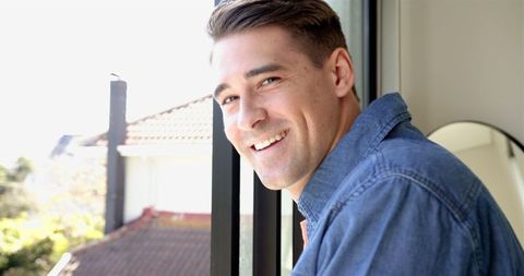 Smiling Man Leaning on Balcony with Scenic Rooftop View