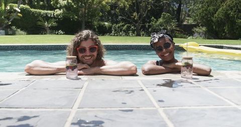 Diverse Couple Relaxing Poolside with Refreshing Drinks Under Sun