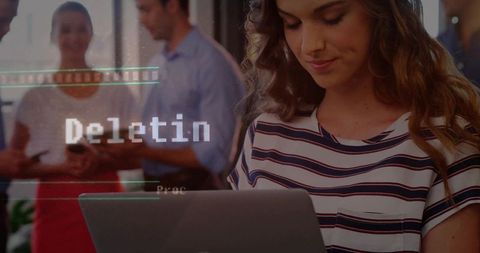 Young Woman Typing on Laptop in Modern Coworking Space with Digital Deleting Overlay