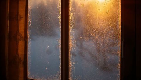 Frosted cabin window catching golden low-angle sunlight through double-pane glass