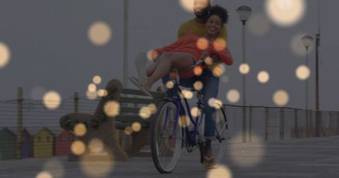 Couple sharing romantic bicycle ride along seaside pier