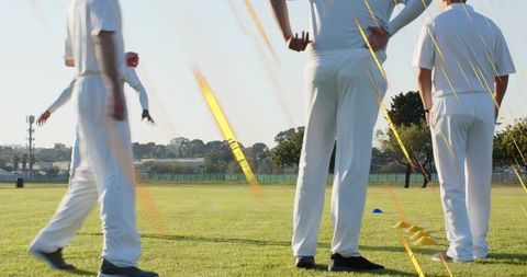 Athletes standing on grass performing agility drills with yellow hurdles and blue cones