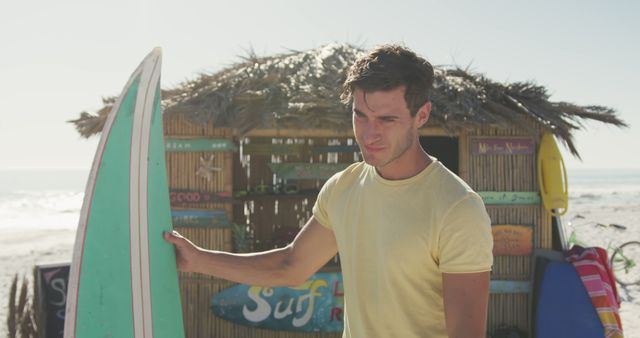 Caucasian man holding blue surfboard at beach house. Summer, free time, chill, vacation, happy time.