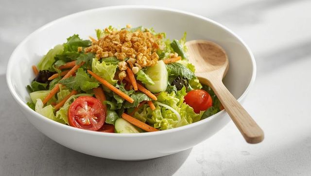 Fresh vegetable salad with chopped nuts in white bowl