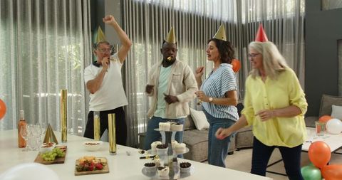 Colleagues joyfully celebrating office party with hats and trumpets