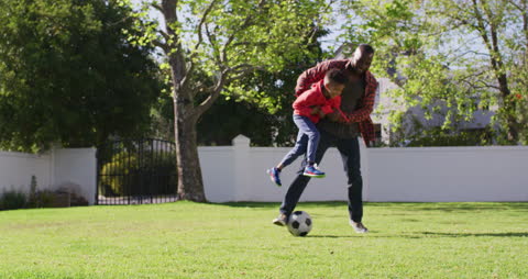 Father and Son Enjoying a Soccer Game in Sunlit Garden