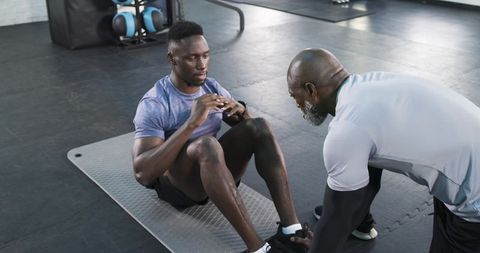 Trainer Motivating Athlete During Sit-ups in Gym Environment