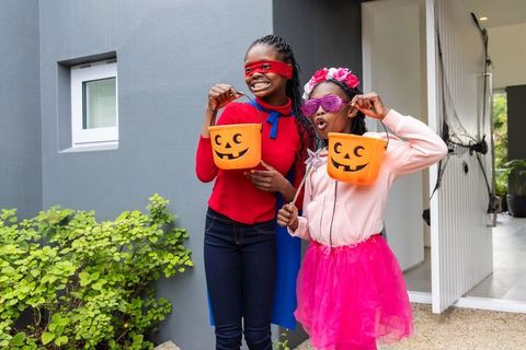 African american girls dressing up in halloween costumes holding jack-o-lantern buckets