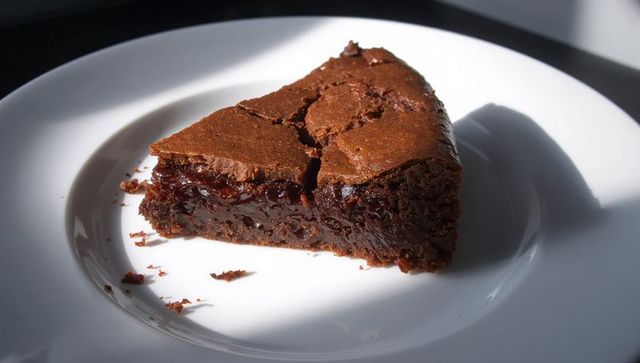 Sunlight highlighting fudgy chocolate cake slice on white plate
