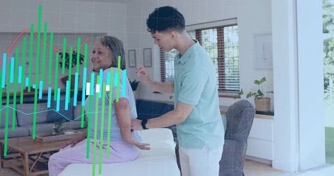 Caregiver steadying senior woman on sofa with digital health and data chart overlay at home