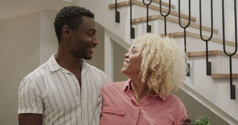 Smiling friends enjoying conversation near staircase at home