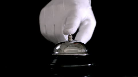 White Gloved Hand Ringing Elegant Service Bell in Darkness