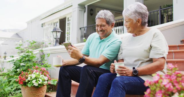 Image of happy biracial senior couple using tablet in garden. active retirement lifestyle, senior relationship and spending time with technology concept.