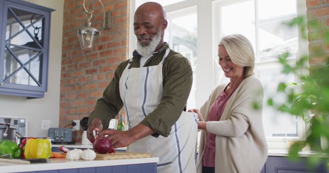 Caucasian senior woman tying apron to her husband in the kitchen at home. retirement senior couple lifestyle living concept